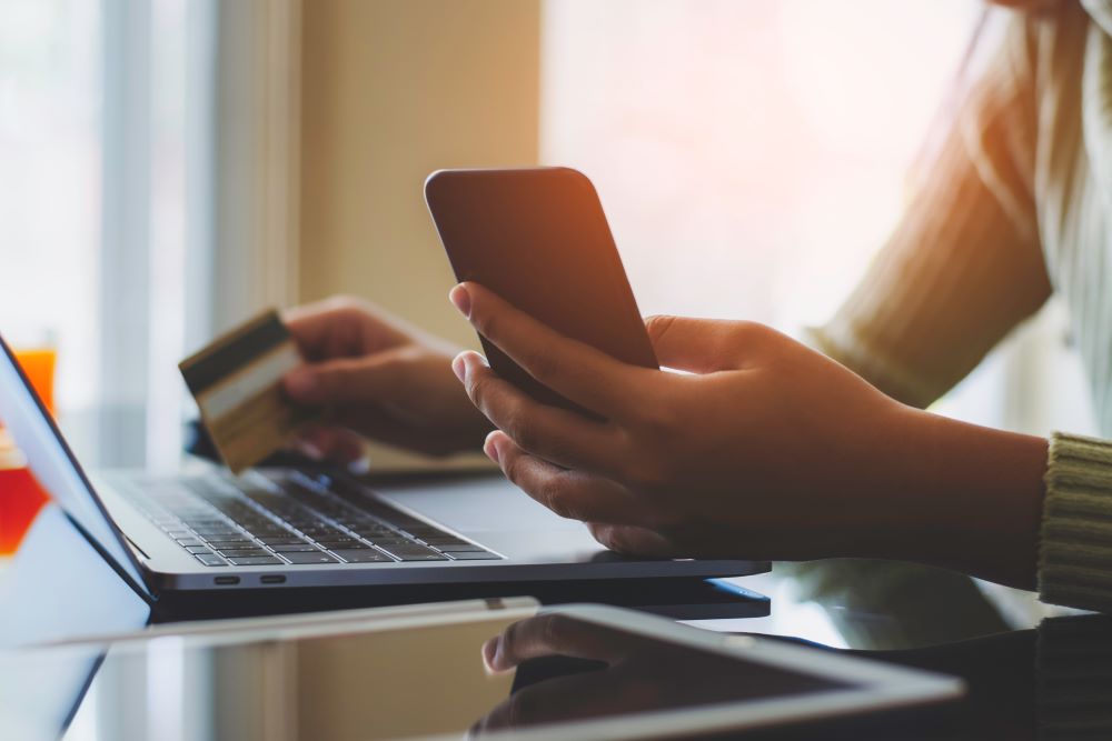 Person holds card and phone while using computer