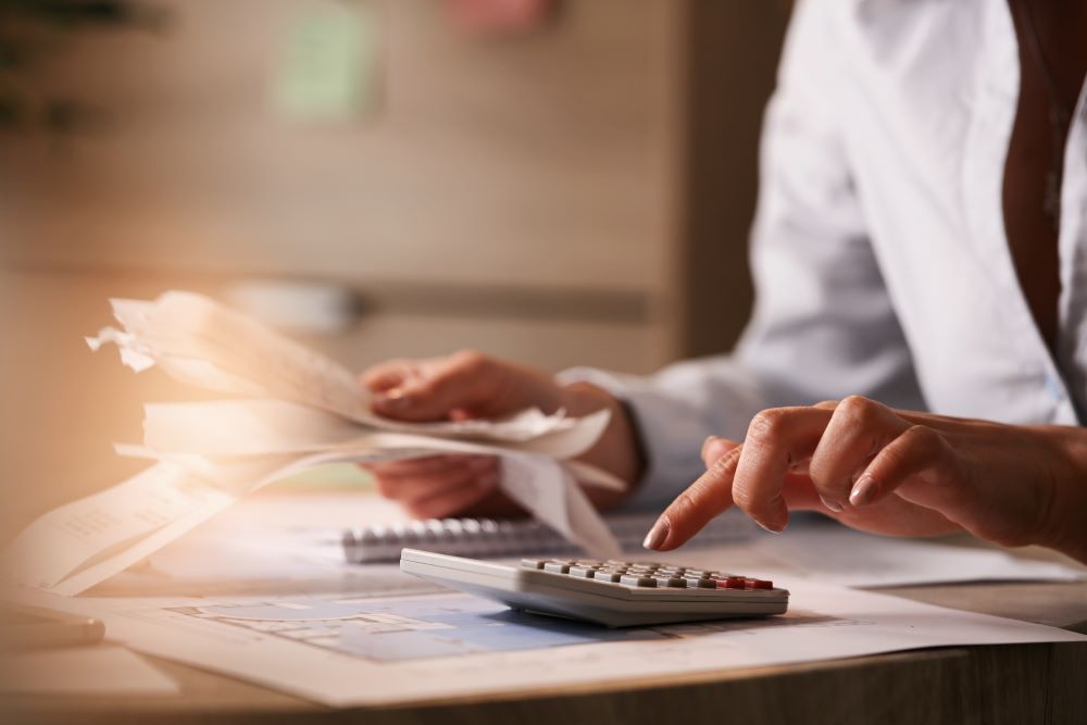 Close up of businesswoman using calculator while going through financial bills