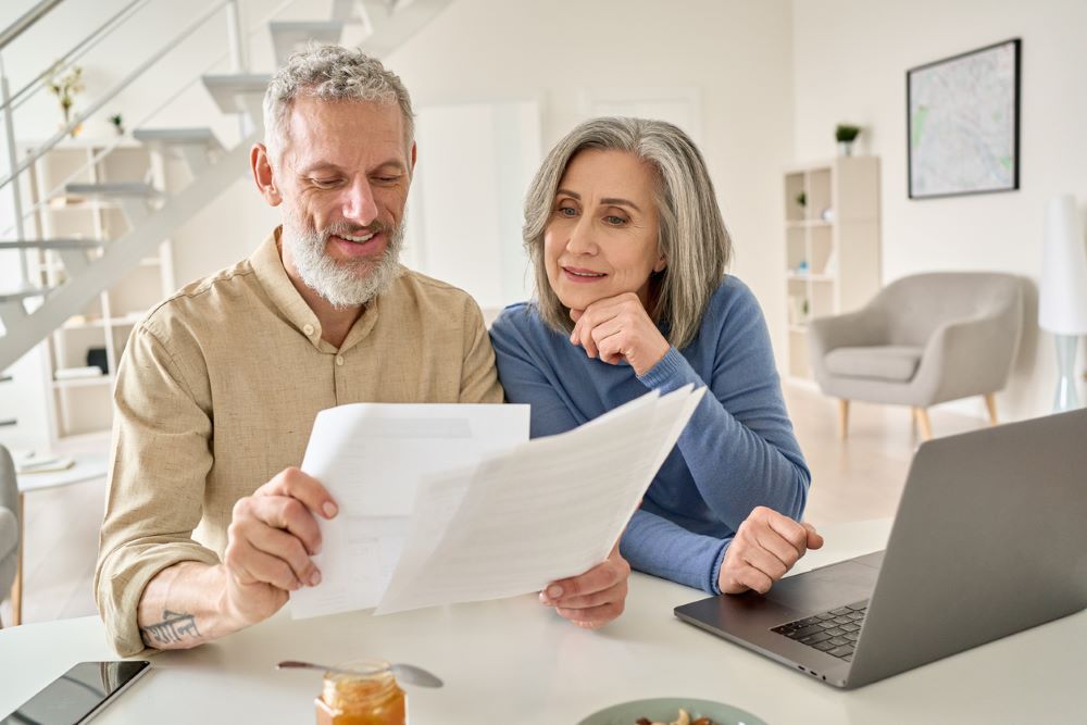 Middle aged couple reading paper bills