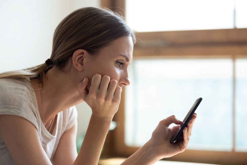 A sad young woman holding smartphone.