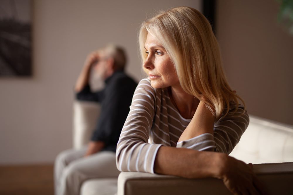 A couple on a couch sitting far apart from each other.