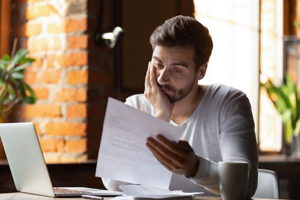 A confused and frustrated man reading letter.