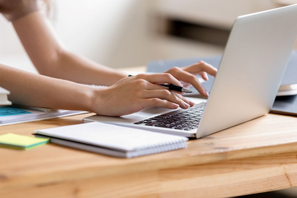Closeup cropped image girl hands typing using laptop