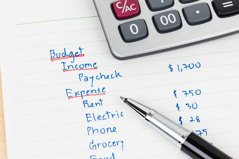 Hand writing home budget with calculator.