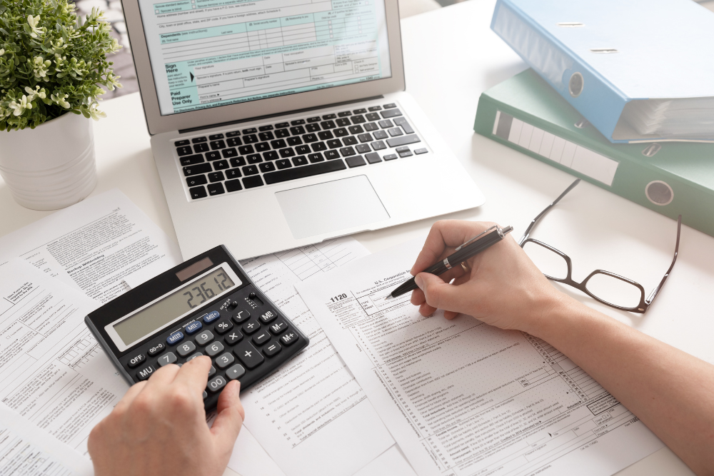 Computer, calculator, and tax papers on a desk.