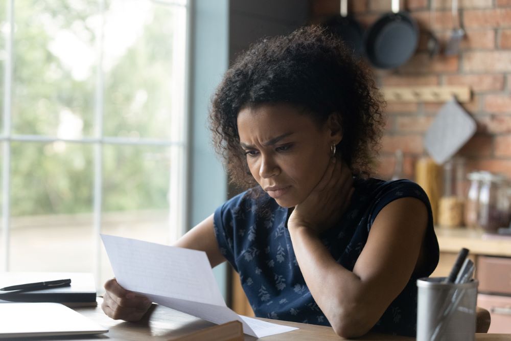 Frustrated young african american woman reading letter with bad news.