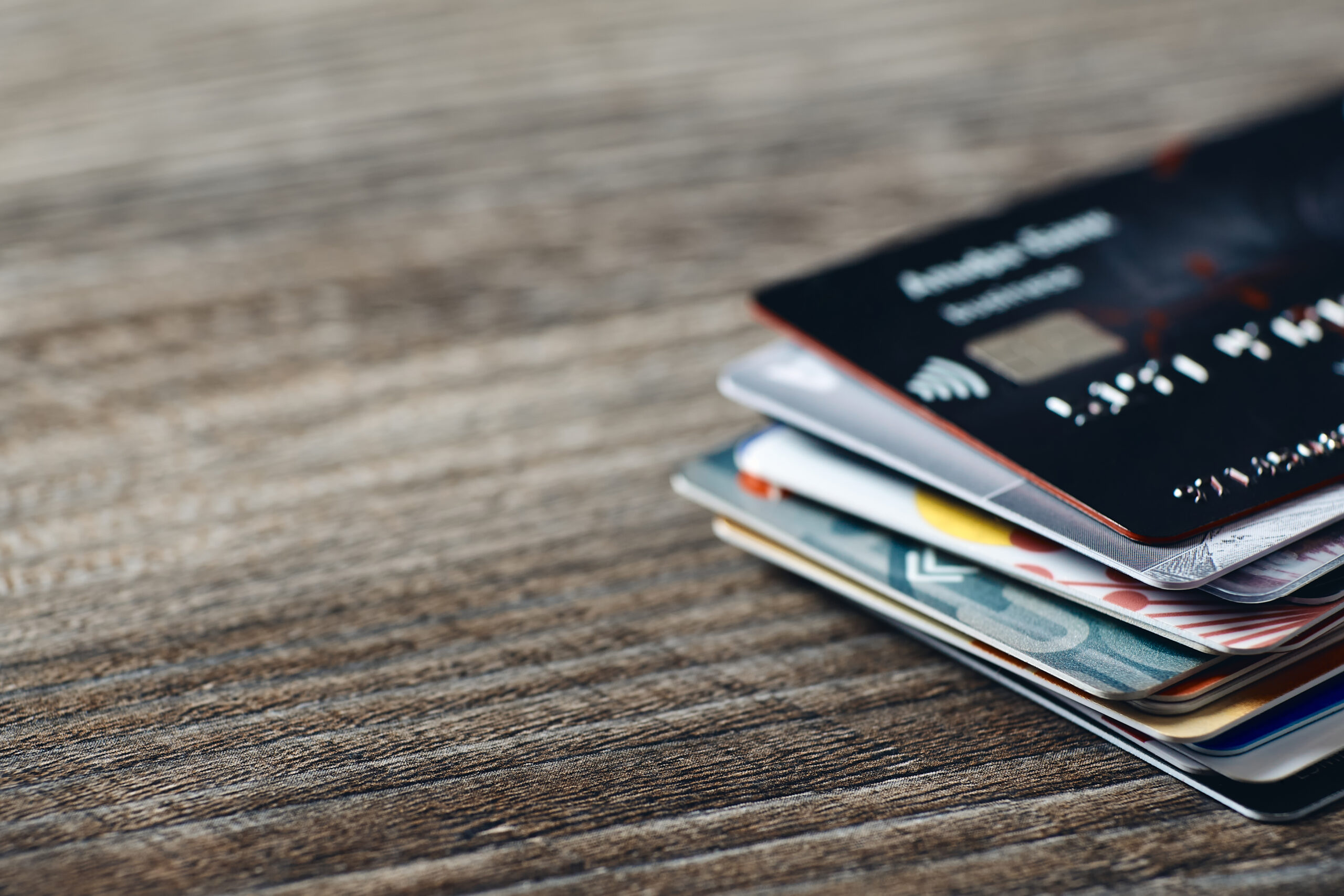 Closeup of many plastic bank cards on a wooden table.