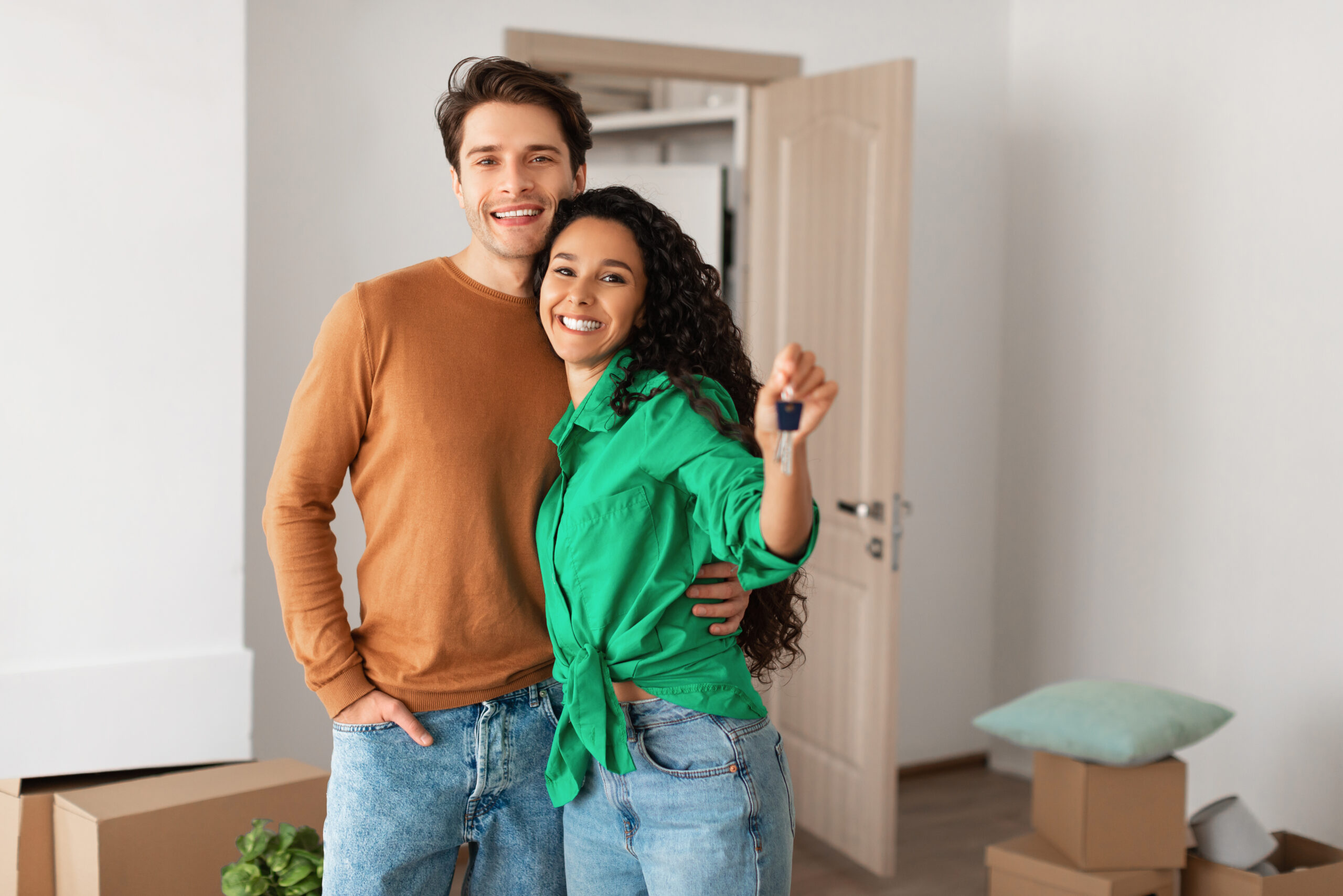 Happy Young Couple Holding Showing Key Standing In New House