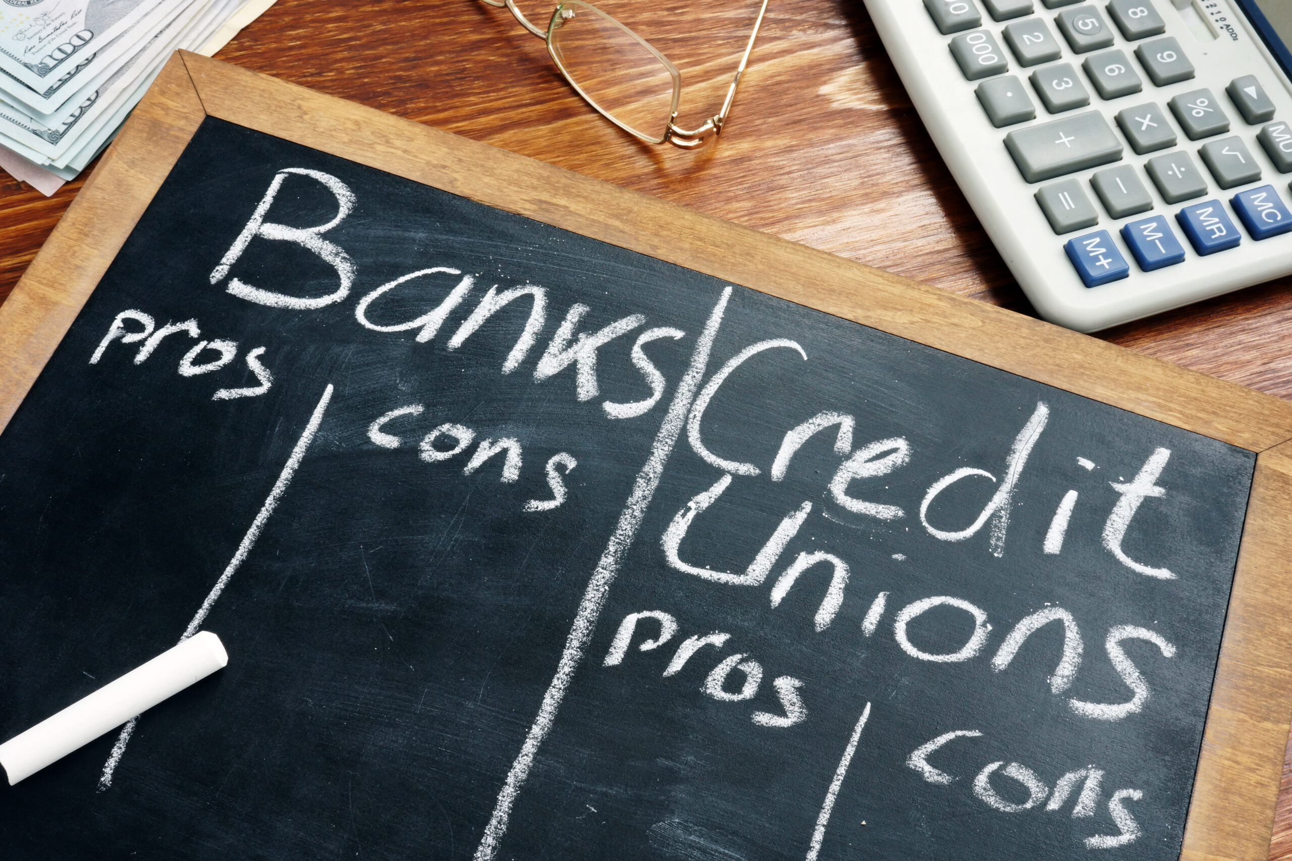 chalk board with the words "banks credit unions" comparing the pros vs cons