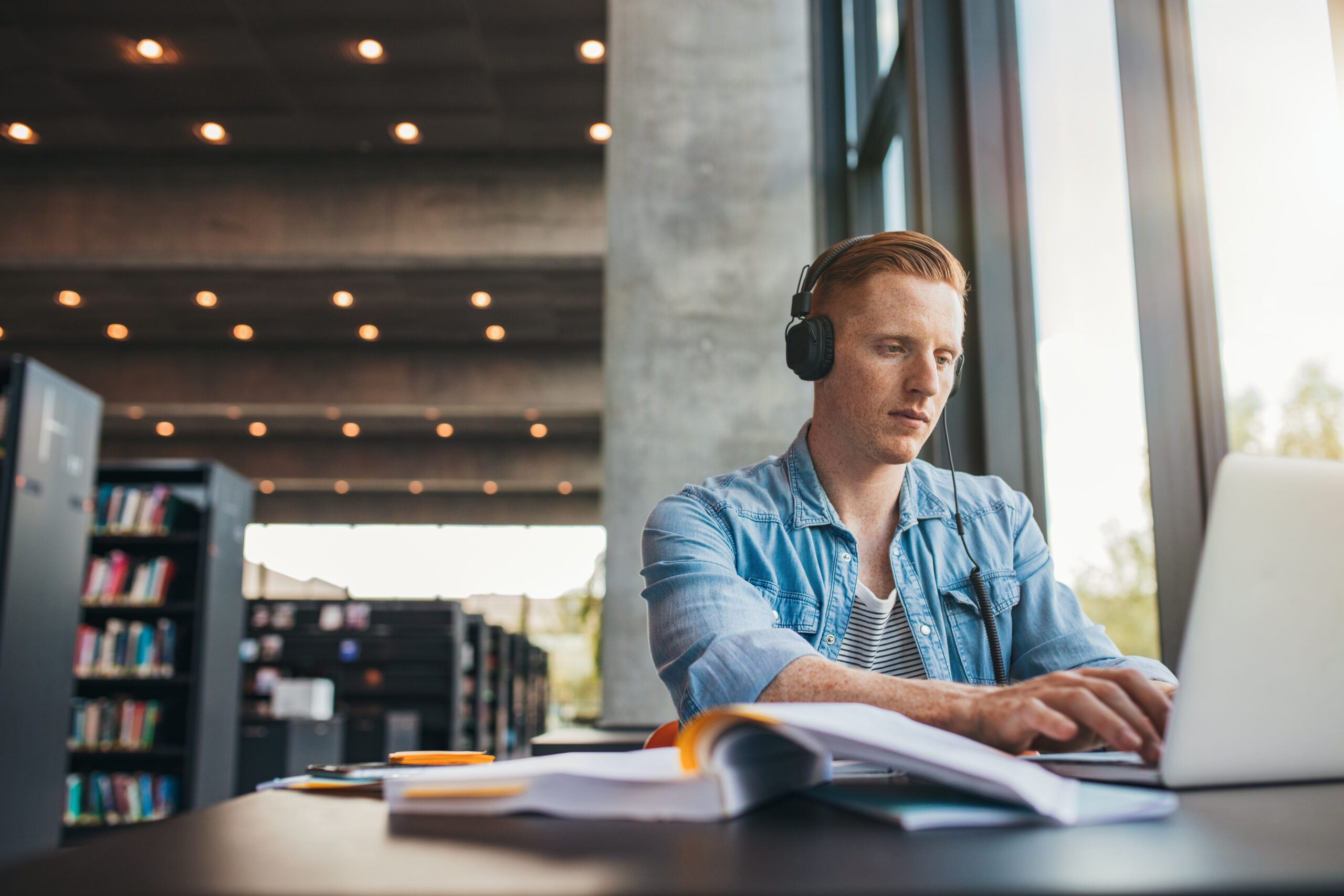 Male student working on laptop at public library