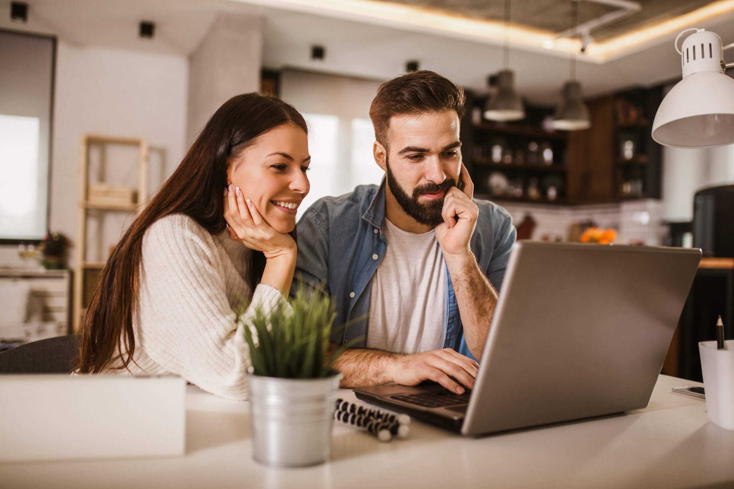 Happy couple doing business together working at home on the laptop.