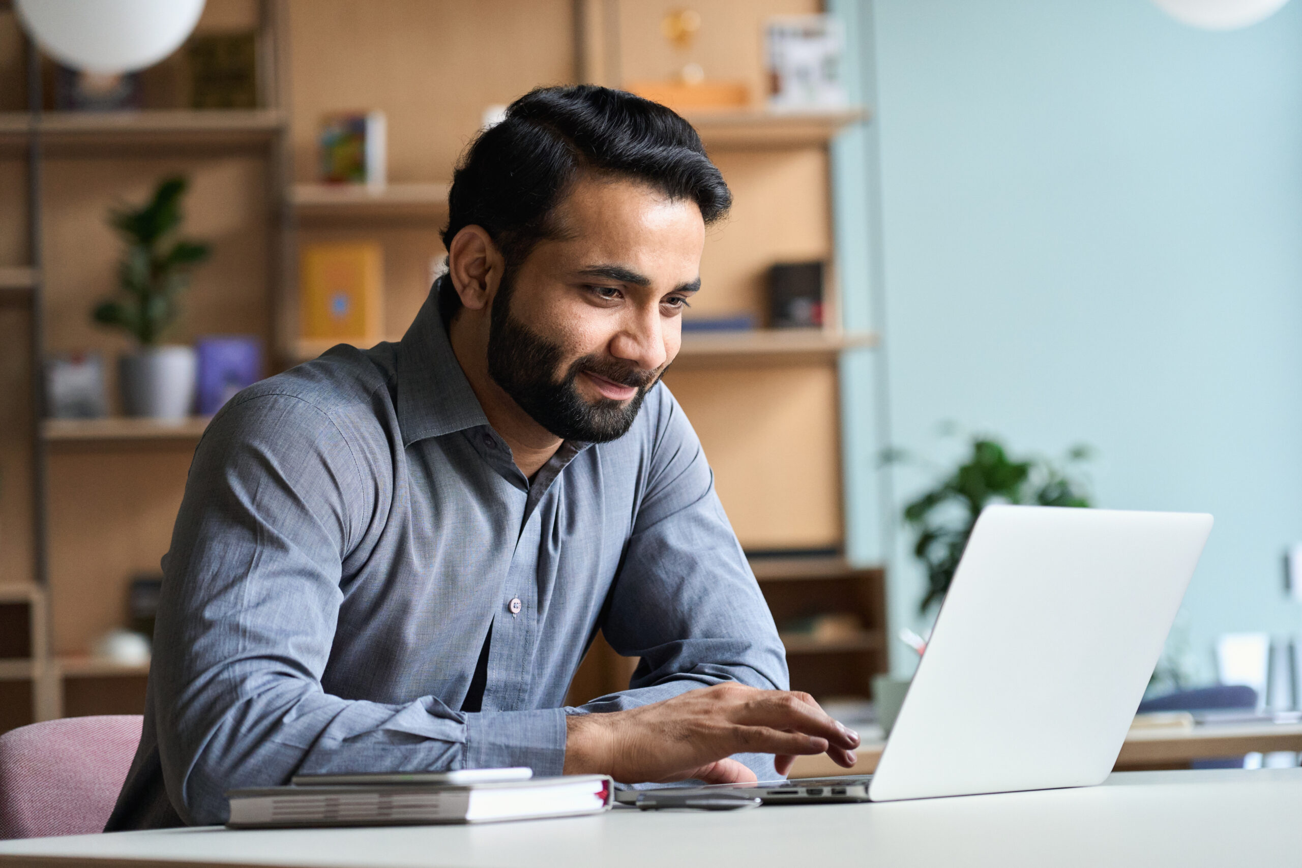 Smiling business man working on laptop at home office.