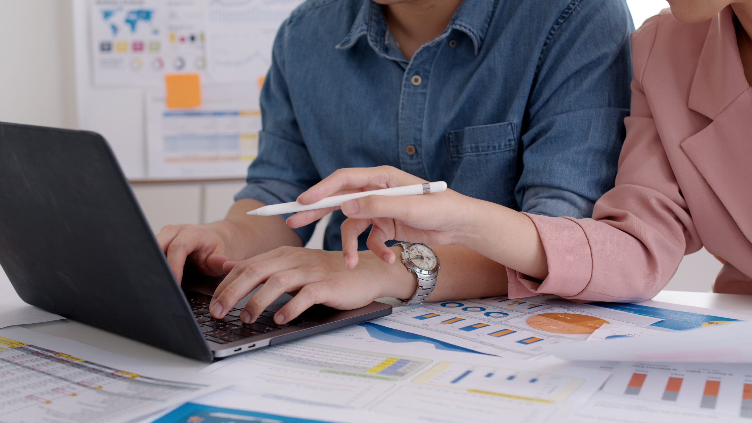 Man and woman working on a report project on laptop.