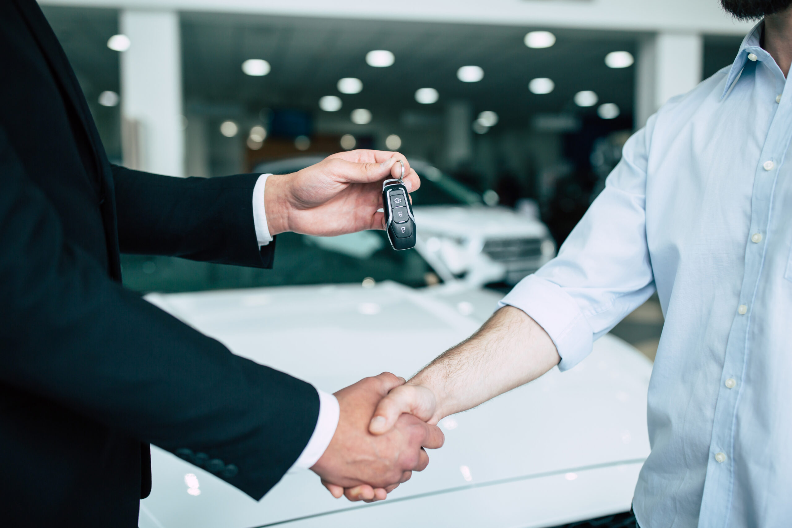 Buying a new car. Handshake and handing over the keys to the car by the salon consultant to the buyer.