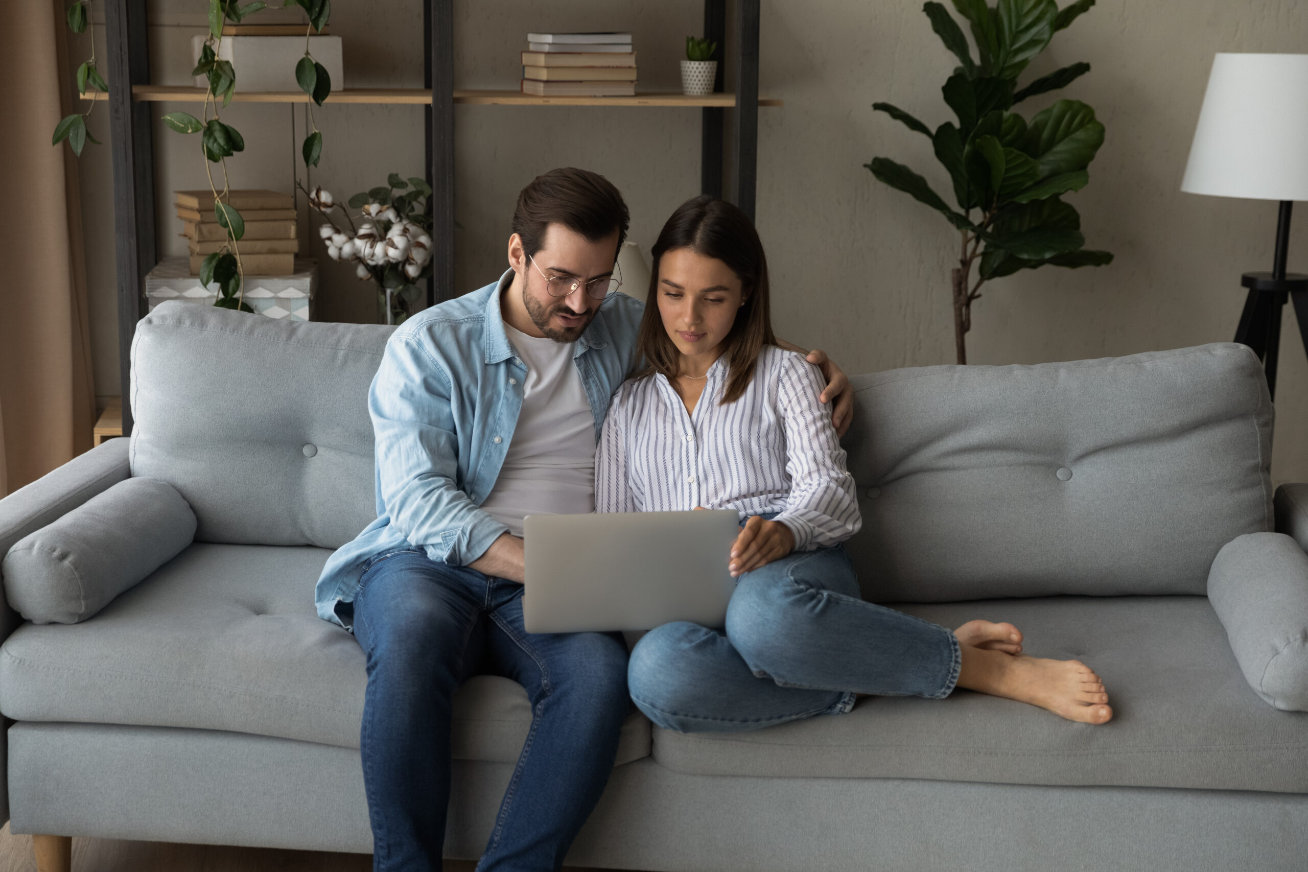 Young couple sitting on couch looking at laptop